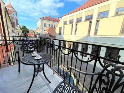 a patio with a table and chairs on a balcony at Picturesque Old Town Apartment with Charming Balcony in Kaunas