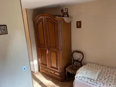 a bedroom with a large wooden cabinet next to a bed at Arbatinės apartamentai - Močiutės namelis in Biržai