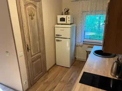 a kitchen with a refrigerator and a microwave on top of it at Arbatinės apartamentai - Močiutės namelis in Biržai
