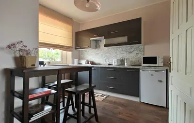 a kitchen with black cabinets and a counter with stools at Vakaro Namai in Alytus