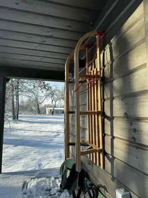 a ladder on the side of a house in the snow at Obuoliu sala Moletu Vila in Gaylyunay