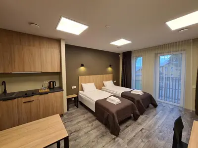 a hotel room with two beds and a kitchen at Airus Apartamentai in Anykščiai