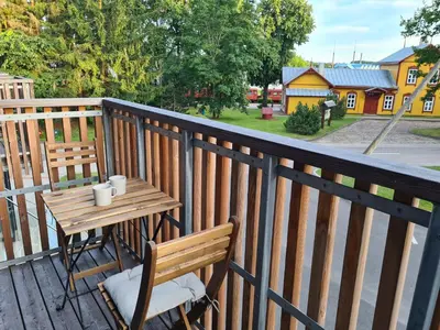 a wooden table and chair on a wooden balcony at Airus Apartamentai in Anykščiai