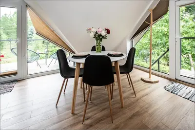 a dining room table with black chairs and a vase of flowers at Rytas cozy apartment in the guest house with the terrace and the stunning view to the river side in Birštonas