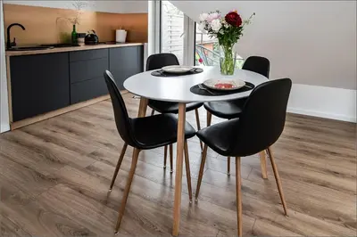a dining room table and chairs with a vase of flowers at Rytas cozy apartment in the guest house with the terrace and the stunning view to the river side in Birštonas