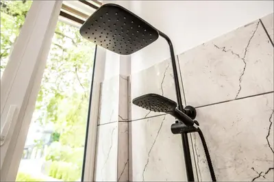 a shower head in a bathroom next to a wall at Rytas cozy apartment in the guest house with the terrace and the stunning view to the river side in Birštonas