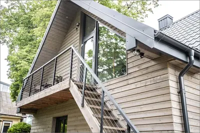 a wooden house with a glass door and stairs at Rytas cozy apartment in the guest house with the terrace and the stunning view to the river side in Birštonas
