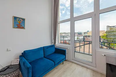 a blue couch in a room with a large window at Mini Loft 1 BD Apt by Domvia in Kaunas