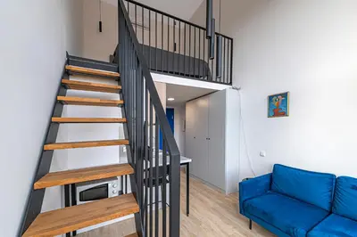 a staircase in a living room with a blue couch at Mini Loft 1 BD Apt by Domvia in Kaunas