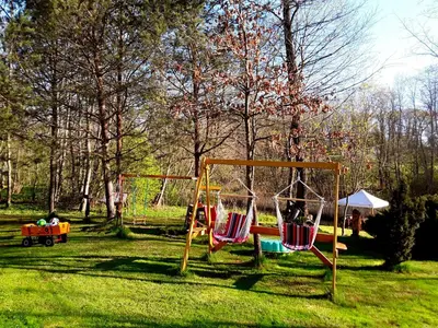 two swings in a yard with a child in a wagon at Taparynė in Alanta