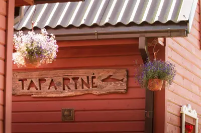 a sign on the side of a red building with plants at Taparynė in Alanta