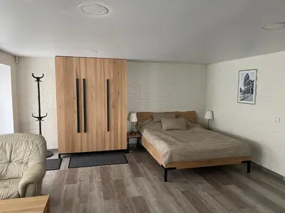 a bedroom with a bed and a wooden cabinet at Pušyno Apartments-Studio in Anykščiai