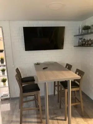 a dining room table with chairs and a television on a wall at Pušyno Apartments-Studio in Anykščiai