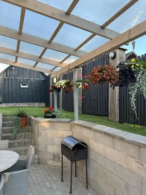 a patio with a grill and a wooden pergola at Pušyno Apartments-Studio in Anykščiai