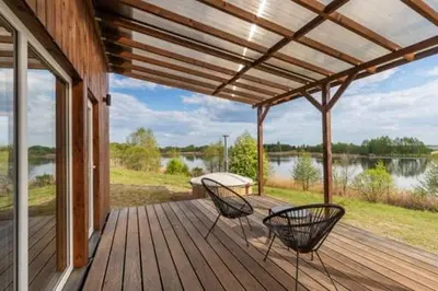 a wooden deck with two chairs and a table on it at Pineplace twins Smilga in Žaugėdai