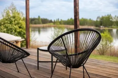 two chairs sitting on a deck with a view of a lake at Pineplace twins Smilga in Žaugėdai