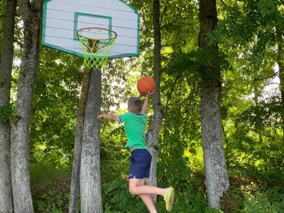 a young boy is throwing a basketball into a hoop at Poilsis ant Virintų ežero kranto in Molėtai