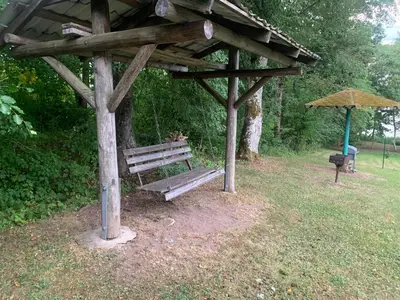 a wooden bench under a pavilion in a park at Poilsis ant Virintų ežero kranto in Molėtai