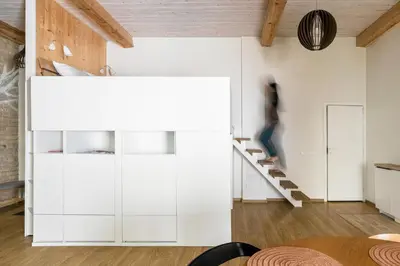 a room with white cabinets and a person walking up the stairs at Cozy studio apartment central in Vilnius