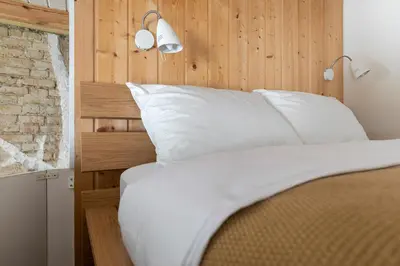 a bedroom with a bed with white sheets and a brick wall at Cozy studio apartment central in Vilnius