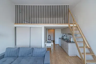 a bedroom with a loft bed and a kitchen at New Town loft apartment with air conditioning by Polo Apartments in Kaunas