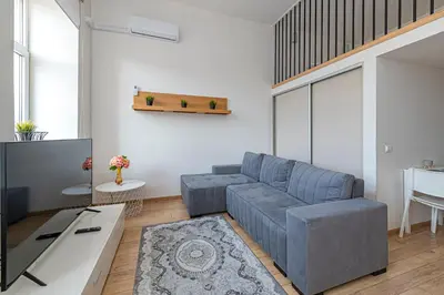 a living room with a couch and a tv at New Town loft apartment with air conditioning by Polo Apartments in Kaunas