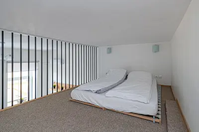 a bed in a white room with a balcony at New Town loft apartment with air conditioning by Polo Apartments in Kaunas