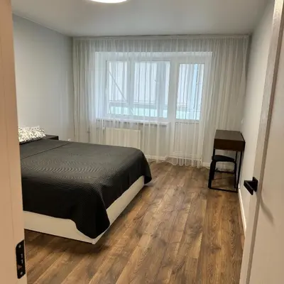 a bedroom with a bed and a table and a window at Cozy Apartment Kazlų Rūda in Kazlų Rūda