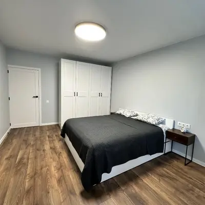 a bedroom with a bed and a wooden floor at Cozy Apartment Kazlų Rūda in Kazlų Rūda
