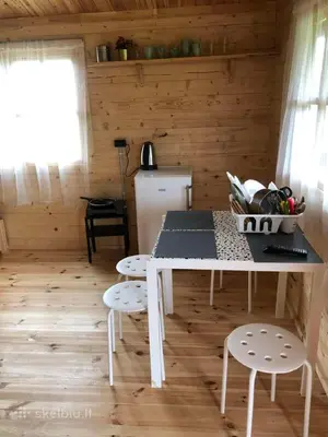 a kitchen with a table and chairs in a cabin at Šeimos Namelis Adomo Sodyboje prie ežero 35 km nuo Vilniaus šalia Dubingių in Dirmeičiai