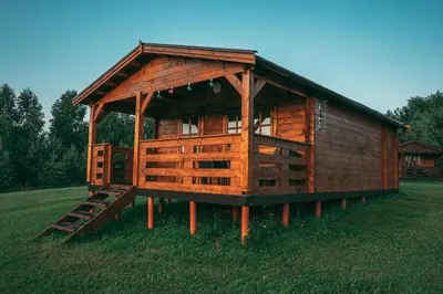 a large wooden cabin in the middle of a field at Šeimos Namelis Adomo Sodyboje prie ežero 35 km nuo Vilniaus šalia Dubingių in Dirmeičiai