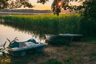 two boats sitting on the shore of a body of water at Šeimos Namelis Adomo Sodyboje prie ežero 35 km nuo Vilniaus šalia Dubingių in Dirmeičiai