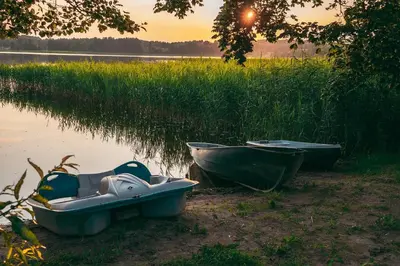 two boats sitting on the shore of a lake at Šeimos Namelis Adomo Sodyboje prie ežero 35 km nuo Vilniaus šalia Dubingių in Dirmeičiai