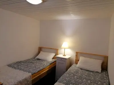 two beds in a small room with a lamp on a night stand at Jono Trobele in Druskininkai