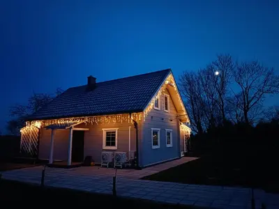 a house with christmas lights on it at night at Arimaičių kaimo sodyba in Arimaičiai