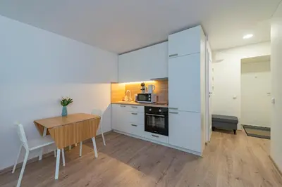 a kitchen with a wooden table and a kitchen with white cabinets at Convenient apartment with balcony by Polo Apartments in Kaunas