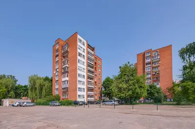 two tall red brick buildings in a parking lot at Convenient apartment with balcony by Polo Apartments in Kaunas