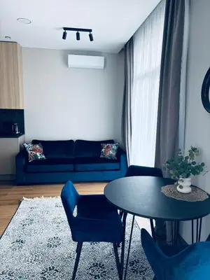 a living room with a table and a blue couch at Ainių gatvės apartamentai in Panevėžys