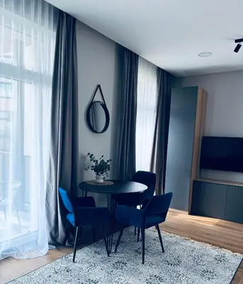 a dining room with a table and blue chairs at Ainių gatvės apartamentai in Panevėžys