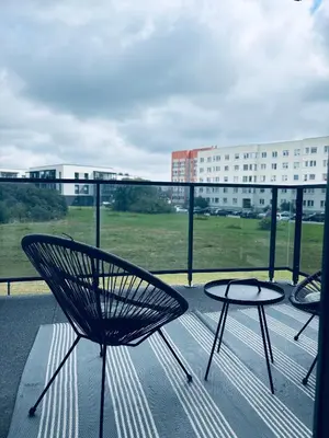 a balcony with two chairs and a table and a building at Ainių gatvės apartamentai in Panevėžys