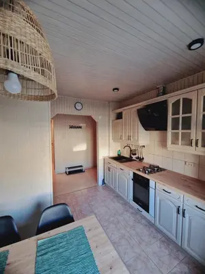 a kitchen with white cabinets and a table with chairs at Apartamentai Sukileliu pr. in Kaunas
