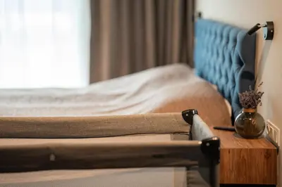 a bedroom with a bed and a wooden table with a vase at Carlo Apartments in Birštonas