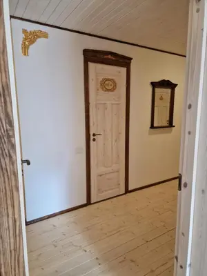 an empty room with a white door and a wooden floor at Skiemonių Dvaras in Skiemonys