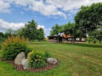 a yard with a house and some flowers and rocks at Anykščiai MĖNULIO AKMUO in Kavoliškis