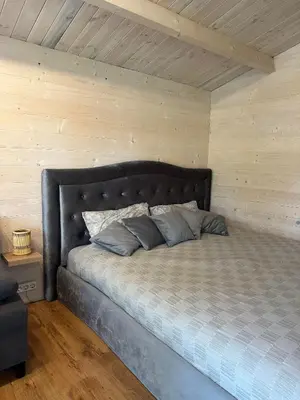 a large bed in a room with a wooden ceiling at Spyglyne in Braziūkai