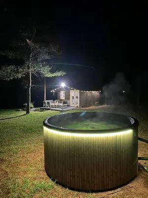 a hot tub in a yard at night at Spyglyne in Braziūkai