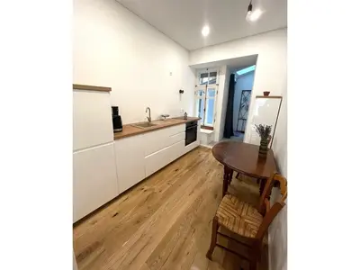 a kitchen with white cabinets and a wooden table at Cozy studio in Sv Stepono g. in Vilnius