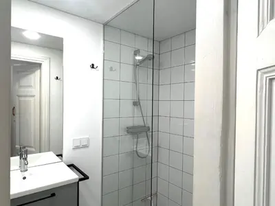 a white bathroom with a shower and a sink at Cozy studio in Sv Stepono g. in Vilnius