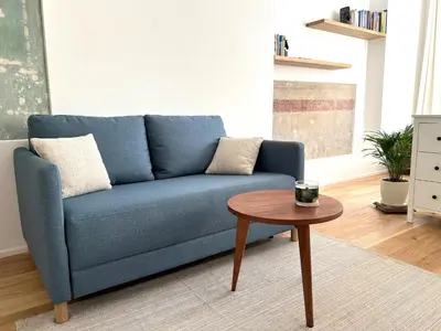 a blue couch in a living room with a table at Cozy studio in Sv Stepono g. in Vilnius