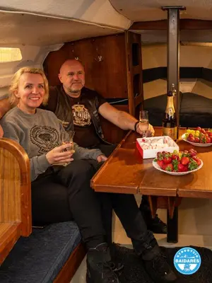 a man and a woman sitting at a table with wine glasses at Uždubysio baidarės Nakvynė Jachtose (Night on a Yacht) in Ariogala
